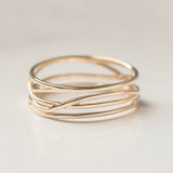 A twisted wide band gold ring with an entwined design, displayed against a neutral background.