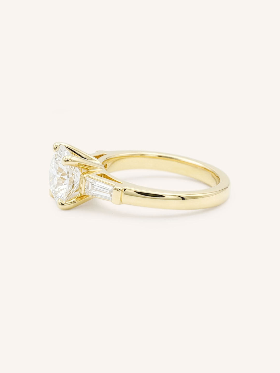 Yellow gold Stately Manor round diamond three stone engagement ring with baguette accents side view