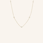 A gold-colored necklace with five bezel-set stones, displayed against a plain background.