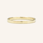 A flat, 2MM wide, gold wedding band on a plain background.