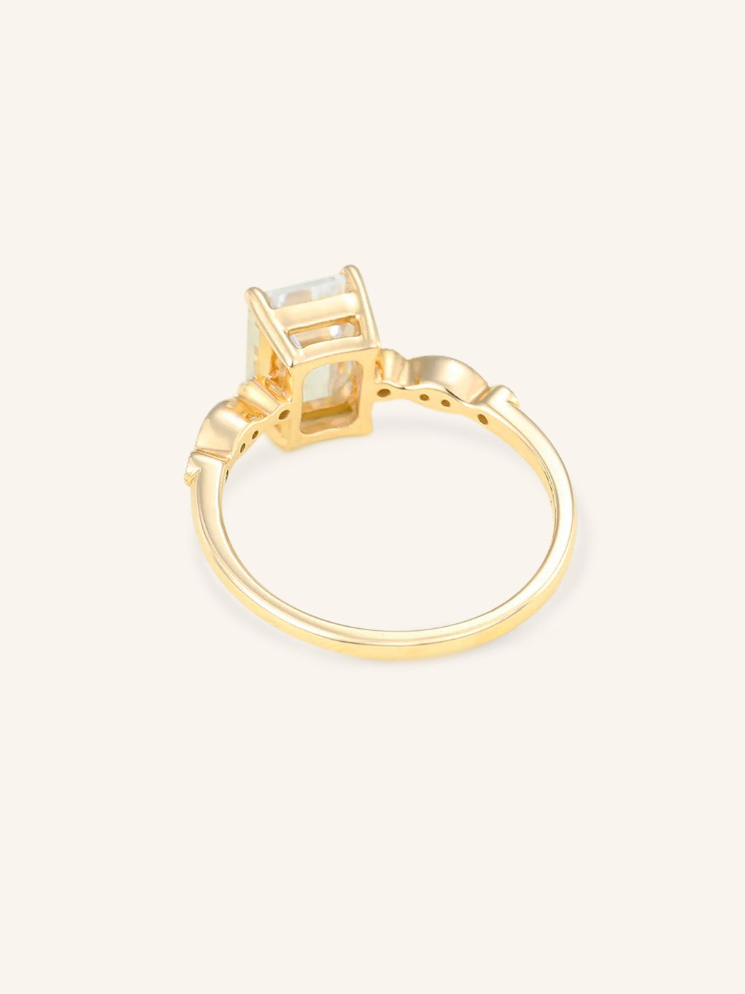 Gold ring with a emerald cut diamond on a light beige background