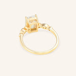 Gold ring with a emerald cut diamond on a light beige background