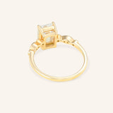 Gold ring with a emerald cut diamond on a light beige background