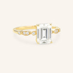 Gold ring with emerald-cut diamond on a white background