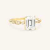 Gold ring with emerald-cut diamond on a white background