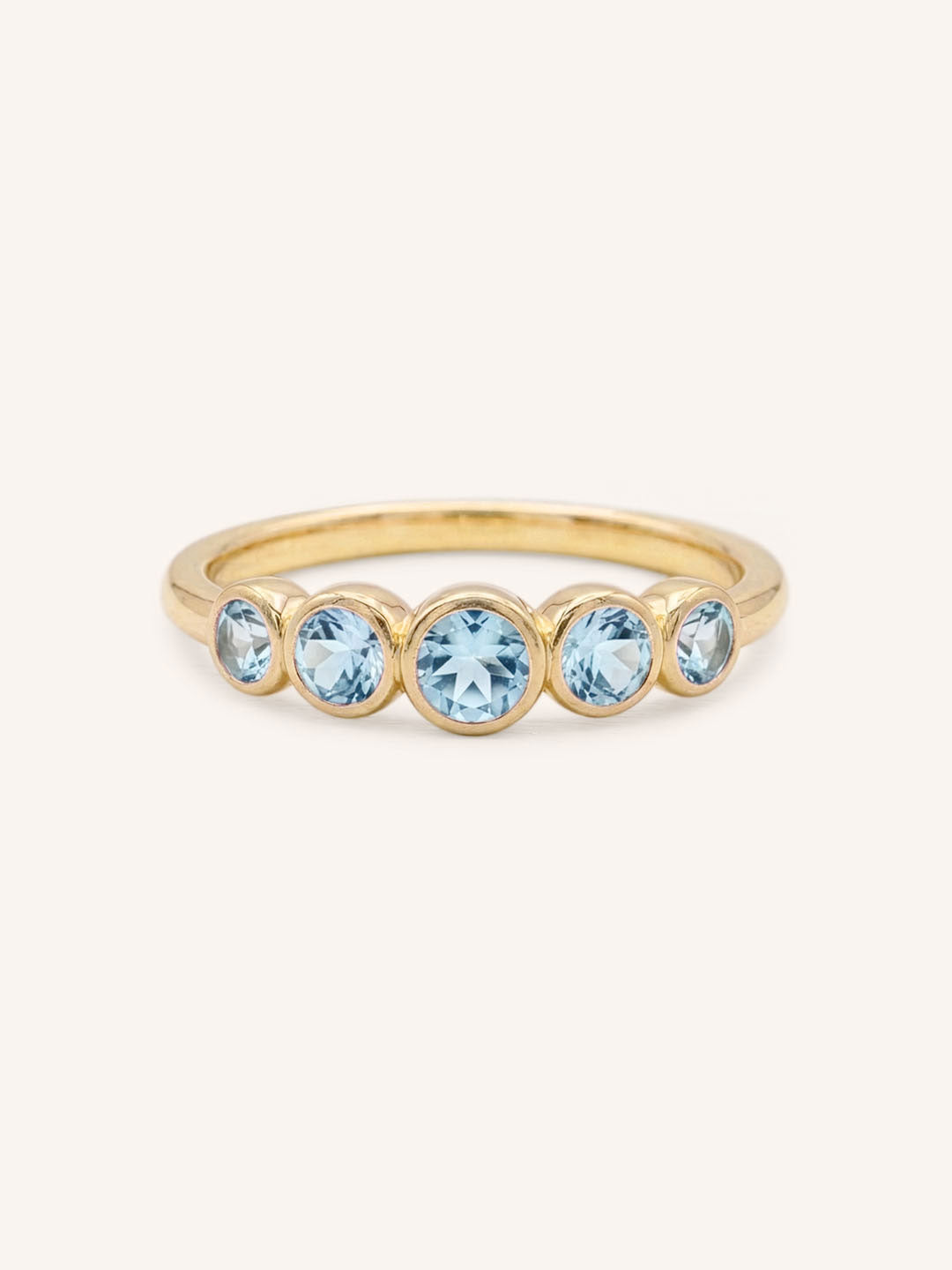 Yellow gold Bonneau five stone aquamarine bezel ring front view on white background