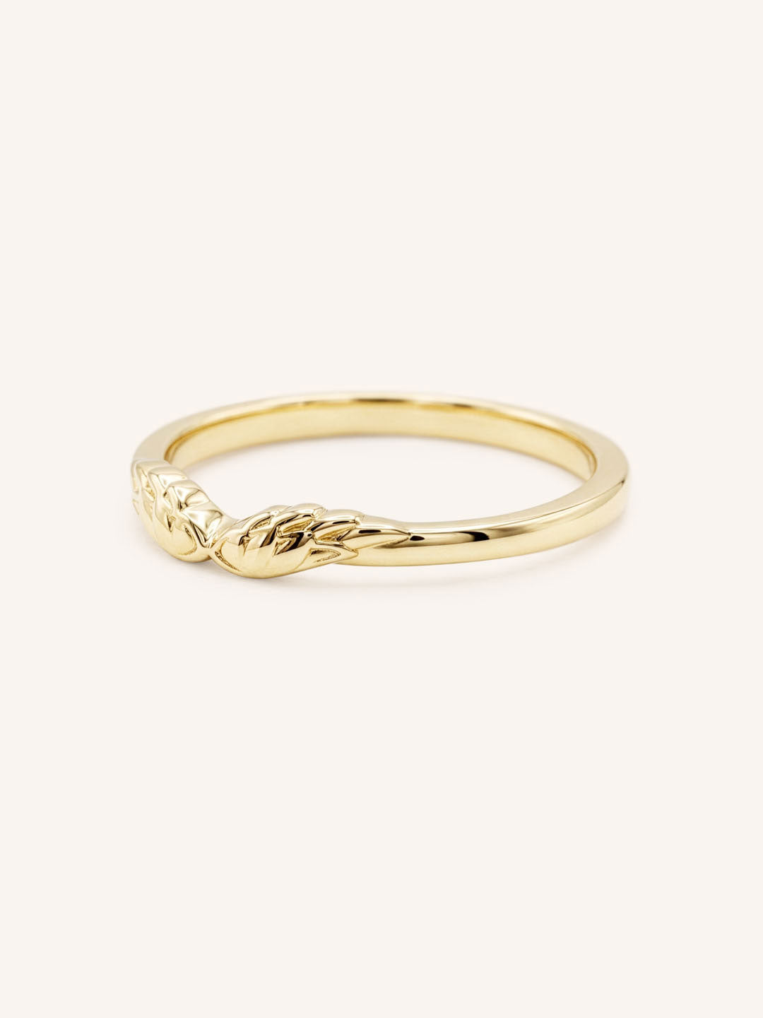 Yellow gold stackable ring with carved angel wings design, side view, on white background